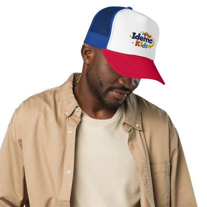 Model wearing an Idemo Kids trucker hat with white front, blue mesh and red visor.